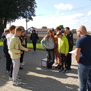 Grupa młodzieży testuje grę planszową na parkingu przy bibliotece