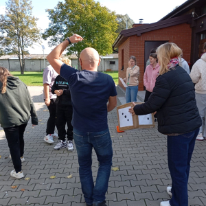 Grupa warsztatowa testuje grę planszową w plenerze.