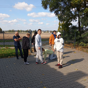 Grupa młodzieży testuje grę planszową na parkingu przy bibliotece