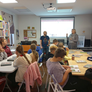 Kierownik biblioteki przedstawia grupie młodzieży prowadzącego.