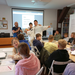 Dwóch cieszących się chłopców stoi przed grupą uczestników