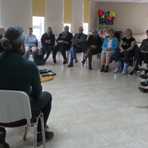 Na zdjęciu widoczni sa uczestnicy spotkania autorskiego, autor siedzi tyłem.