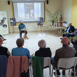 Autor opowiadania o swojej książce, uczestnicy spotkania przysłuchują się jego wypowdzi.
