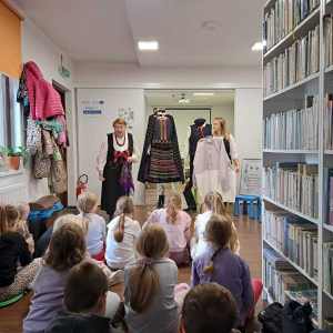 Dwie panie z KGW pokazują dzieciom dawny strój ludowy.