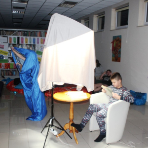 Chłopiec czyta pod lampą osłoniętą szalem