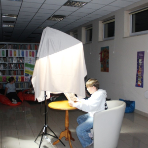 Chłopiec czyta pod lampą osłoniętą szalem