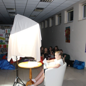 Dziewczynka czyta pod lampą osłoniętą szalem