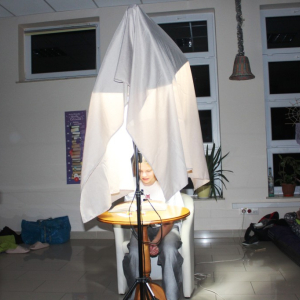 Postać czyta pod lampą osłoniętą szalem