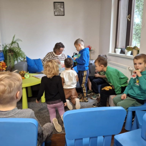 Dzieci słuchają czytanego przez bibliotekarkę opowiadania o jesieni