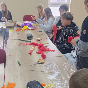 Młodzież i kobieta robią kwiaty z bibuły