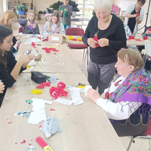 Młodzież i kobieta robią kwiaty z bibuły