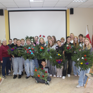 Uczestnicy i prowadzący pozują do zdjęcia z koronami nagrobnymi