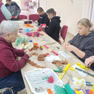 Młodzież i kobieta robią kwiaty z bibuły