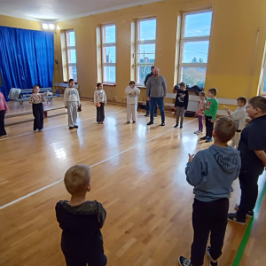 Dzieci stoją w kole, prowadzący tłumaczy zasady zabawy - Papuga