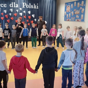 Dzieci stoją w okręgu trzymając się za ręce.