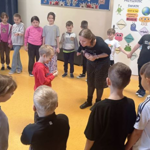 Dzieci stoją w okręgu w środku prowadząca rozmawia z chłopcem