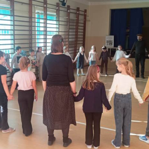 Dzieci i prowadzący warsztaty stoją w okręgu trzymając się za ręce