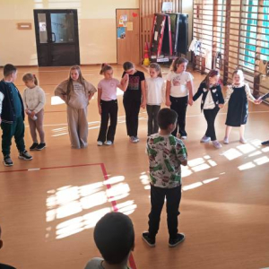 Dzieci i prowadzący warsztaty stoją w okręgu trzymając się za ręce