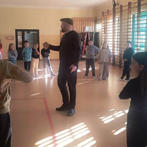 Dzieci stoją w okręgu po środku stoi mężczyzna