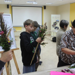 Dwaj chłopcy i kobieta pracują nad palmami wielkanocnymi