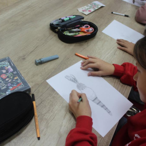 Dziewczyna siedzi przy stole pracując na rysunkiem palmy