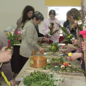 Uczetnicy warsztatów wraz z prowadzącymi pracują nad palmami wielkanocnymi