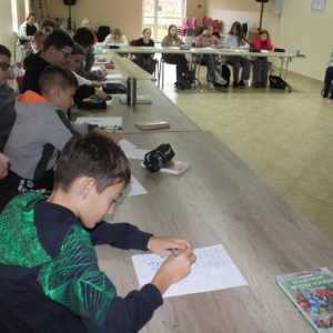 Uczestnicy warsztatów notują przy stołach