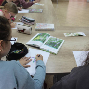 Dziewczynka przerysowuje kwiat z leżącej przed nią książki