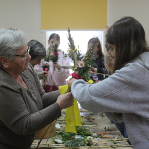 Prowadząca pokazuje dziewczynie, jak układać palmę wielkanocną
