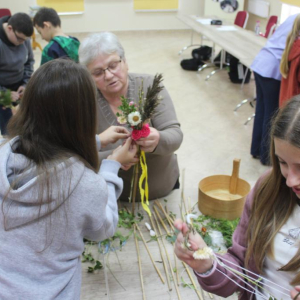 Prowadząca pokazuje dziewczynie, jak układać palmę wielkanocną