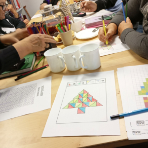 Stół z materiałami plastycznymi do wykonania Kalendarza Adwentowego, w tle seniorzy przy pracy