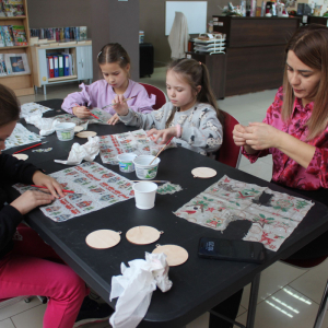 Dzieci pracują nad własnoręcznie wykonywanymi bombkami podczas bożonarodzeniowych warsztatów w bibliotece.