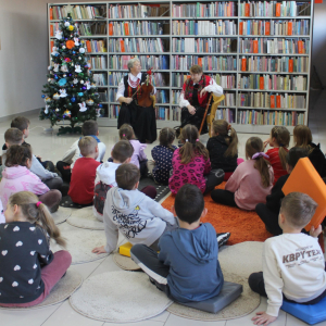 * Pani Natalia opowiada dzieciom o tradycjach bożonarodzeniowych podczas spotkania w bibliotece, dzieci słuchają