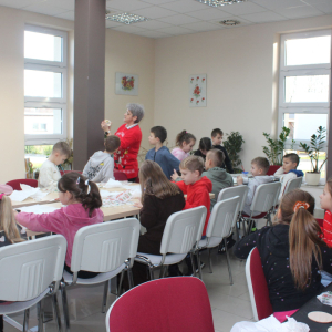  Pani Edyta pokazuje dzieciom, jak prawidłowo wykonać ozdobę na bombce metodą decoupage podczas warsztatów w bibliotece.