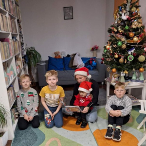Bibliotekarka przy choince czyta dzieciom świąteczną opowieść