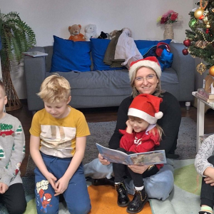 Dzieci z bibliotekarką siedzą na dywanie przy choince