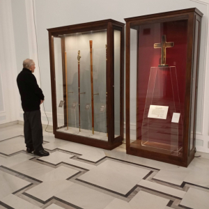 Mężczyzna stoi przed gablotą z laskami marszałkowskimi.