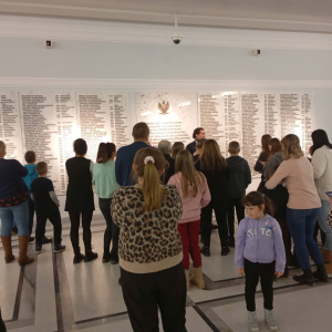 Przewodnik omawia grupie zwiedzających tablicę poświęconą parlamentarzystom poległym podczas II wojny światowej.