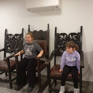 Dwie dziewczynki na ozdobnych fotelach sejmowych.
