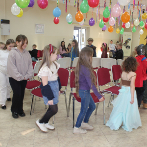 Dzieci w kostiumach biorą udział w zabawie ruchowej w udekorowanej sali.