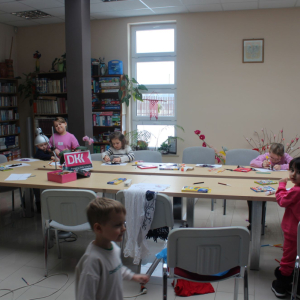 Dzieci wykonujące prace plastyczne przy stole w bibliotece.