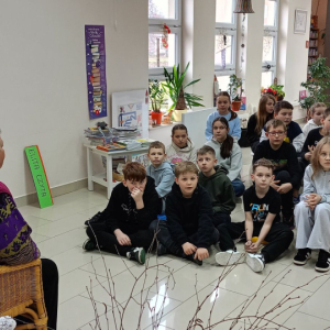 Na krześle siedzi prowadząca zajęcia ,przed nią na dywanie siedzą dzieci.