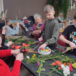 Przy stole dzieci oraz prowadzące wykonują palmy wielkanocne.