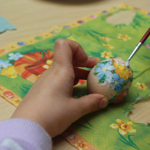 Dziecko maluje pisankę.