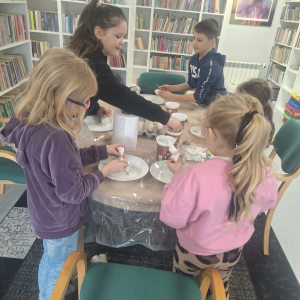 Przy stole dzieci malują pisanki.