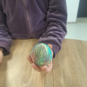 Dziewczynka trzyma w ręce kolorową pisankę.