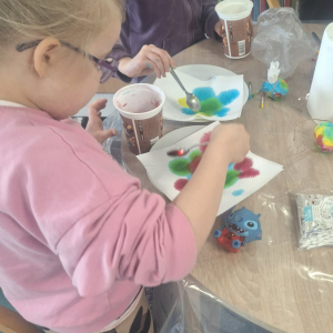 Dziewczynka maluje nakolorowo papierowy ręcznik.