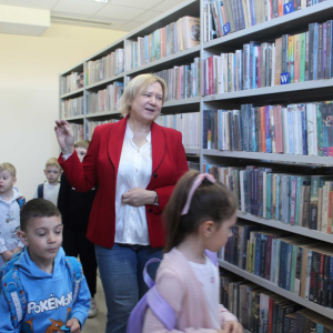 Dzieci i bibliotekarka pomiędzy regałami z książkami