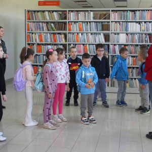 Grupa dzieci stoi przed bibliotekrką w wypożyczalni