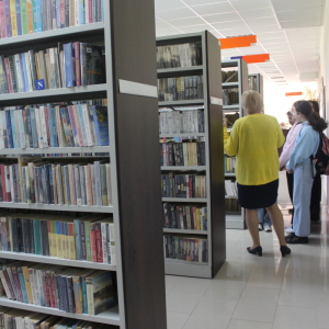 Bibliotekarka oprowadza ucznió po bibliotece.